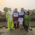 GFM visitors stand near stacked bricks at a kiln community in Pakistan