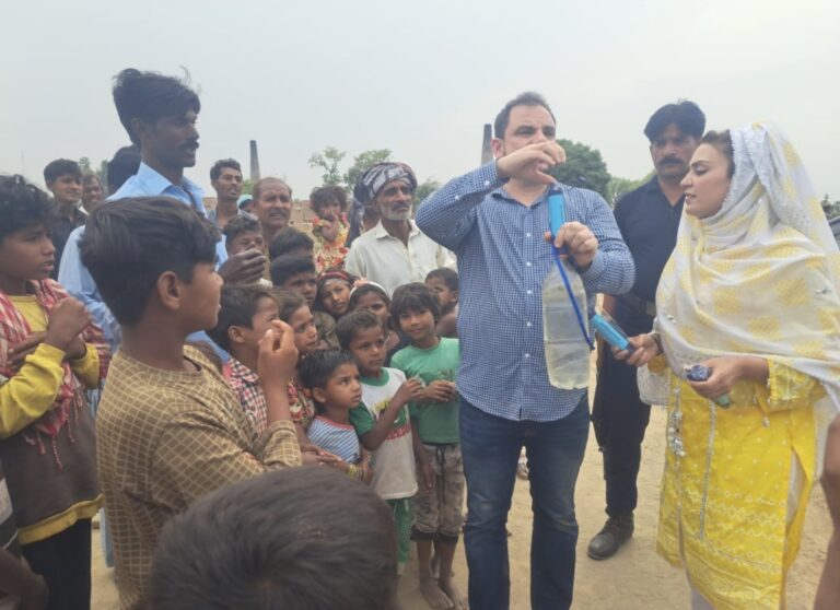Christopher demonstrates a portable water filter to families during a GFM visit in Pakistan